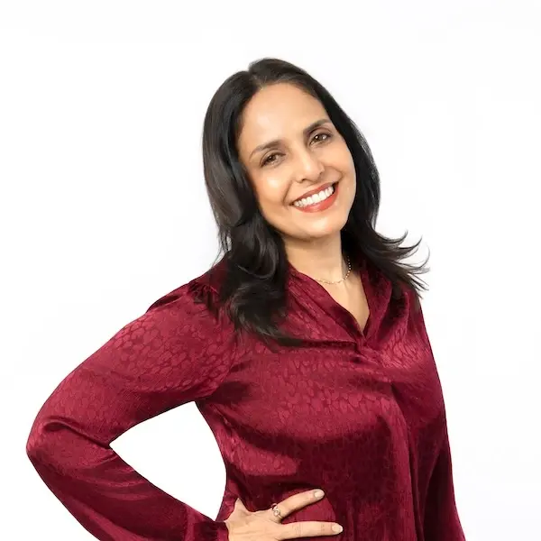 Professional female dentist in maroon scrubs smiling at Plantation dental practice.