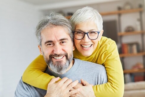 Happy mature couple smiling together in Plantation dental office.