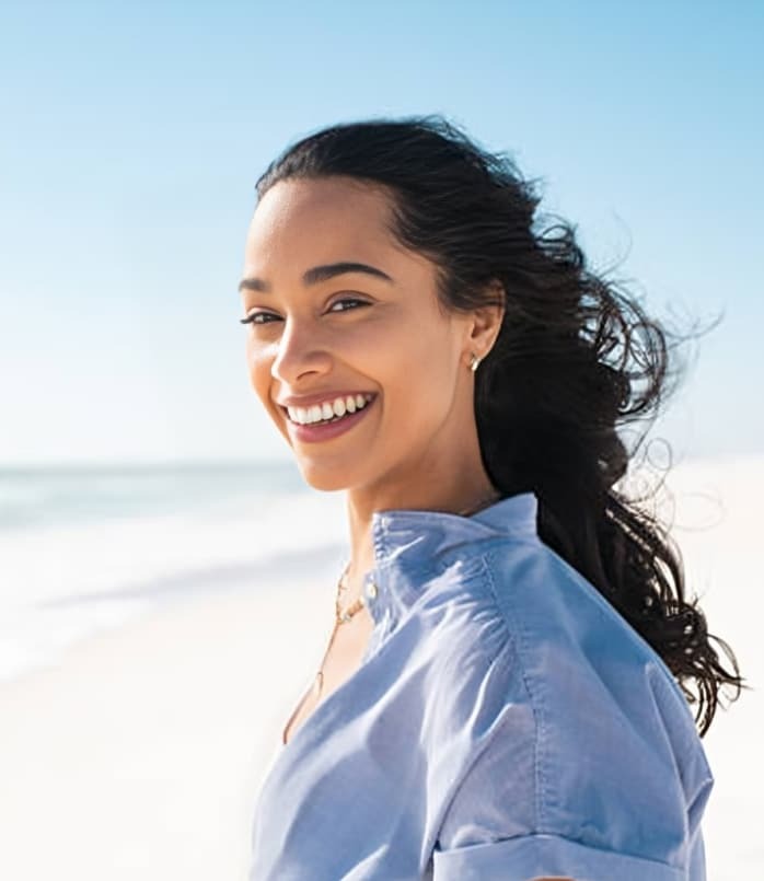 Smiling woman at Plantation beach in blue shirt enjoying a bright, healthy smile.