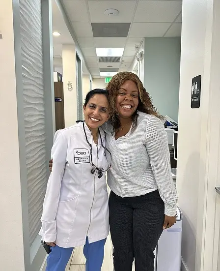 Smiling dentist and patient in a modern dental office hallway in Plantation, FL.