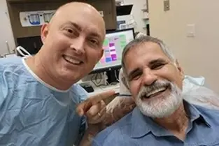 Two smiling men posing together at a dental practice in Plantation, Florida.
