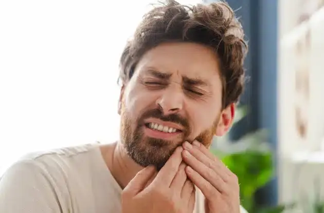 Man holding his cheek in pain, representing emergency dental care needs in Plantation, FL.