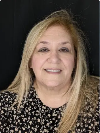 Woman smiling wearing a floral patterned black top, likely a dental provider in Plantation, FL.