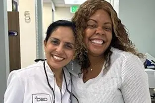 Two dental professionals smiling together in a clinical setting in Plantation, FL.
