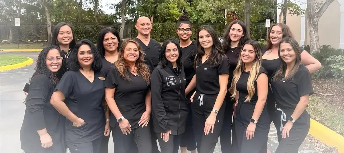 Dental team in black uniforms smiling together outdoors in Plantation, Florida.