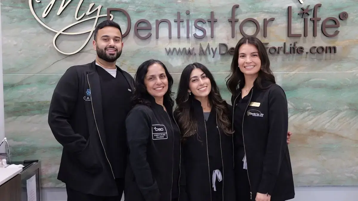 My Dentist for Life team smiling in front of dental practice signage in Plantation, FL.
