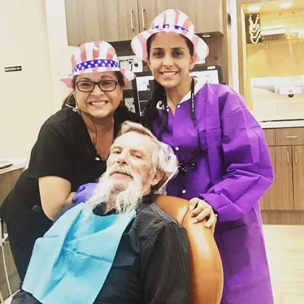 Two dental professionals celebrate with a senior patient wearing patriotic hats on Veterans Day.