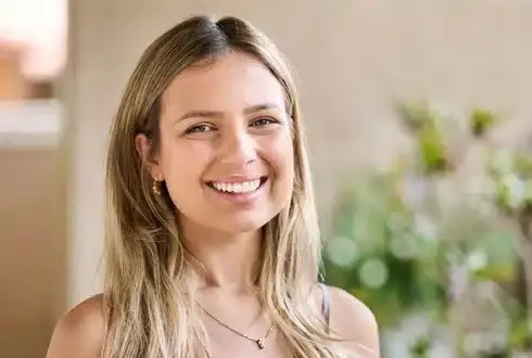 Smiling woman in dental office with plants in background.