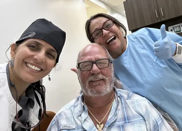 Smiling dental team and patient in Plantation, FL dental office.