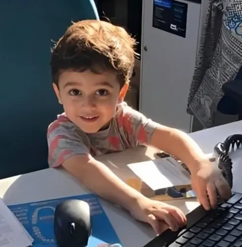 Young child smiling at dental office computer workstation in Plantation, FL.