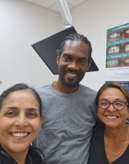 Three smiling dental professionals posing together in a Plantation, FL dental office.