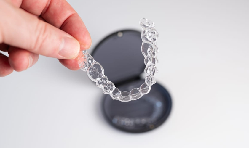Clear aligner tray being held up to show the transparent plastic teeth straightening device.